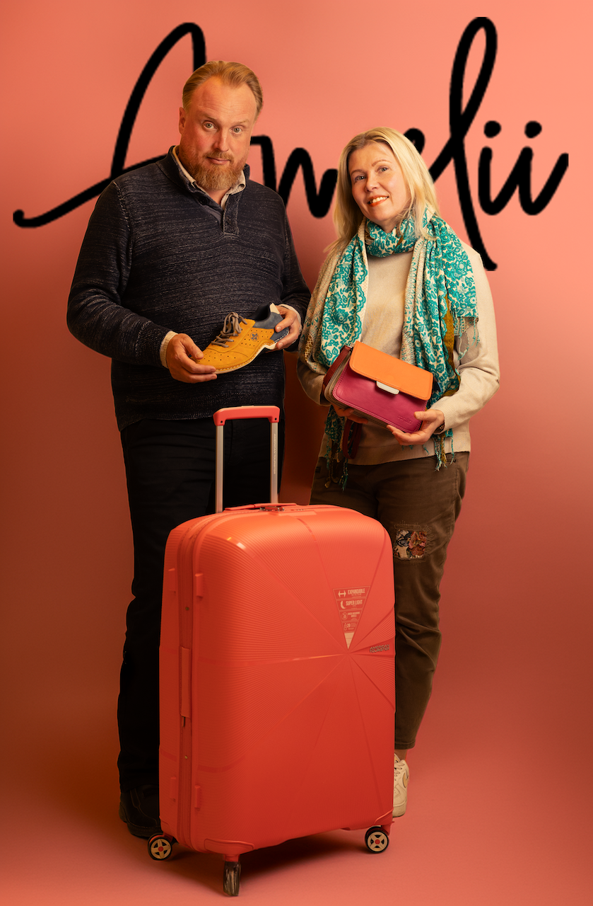 Anni ja Matti Lindell esittelevät kenkiä ja laukkua Amelii-logon edessä