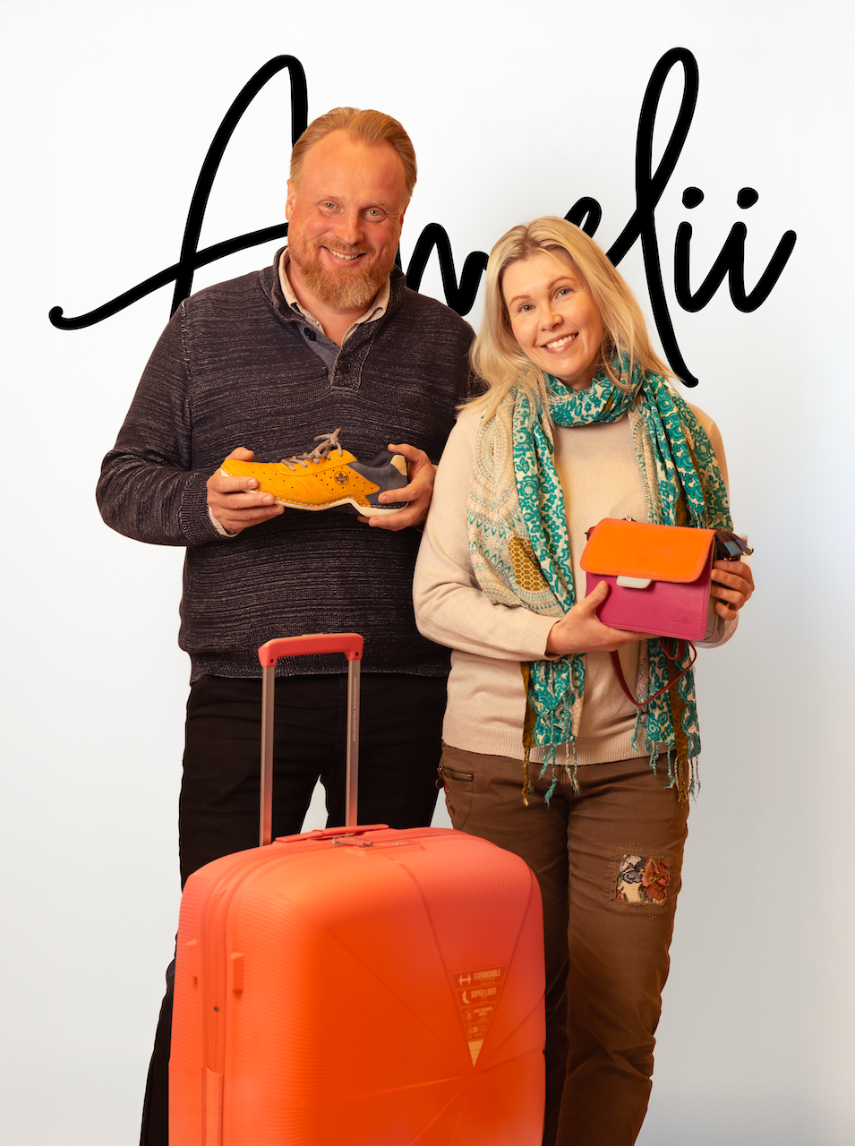 Anni ja Matti Lindell esittelevät kenkiä ja laukkua Amelii kenkä ja laukku -logon edessä